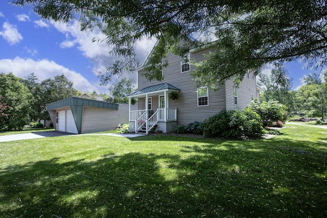 view of front of property featuring a garage, a front yard, and an outbuilding