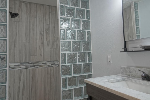 bathroom with a tile shower and vanity