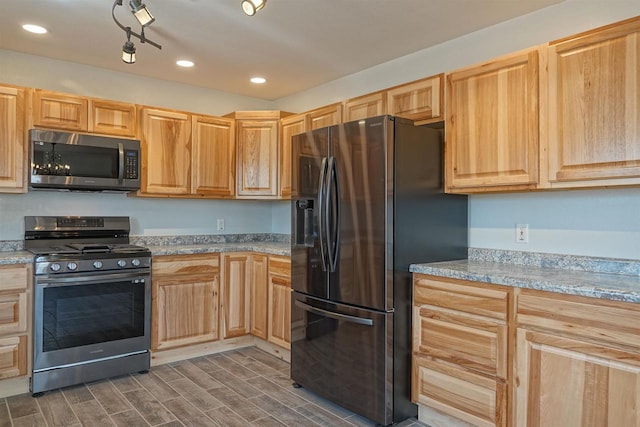 kitchen with light brown cabinetry, light stone countertops, dark wood-type flooring, and appliances with stainless steel finishes