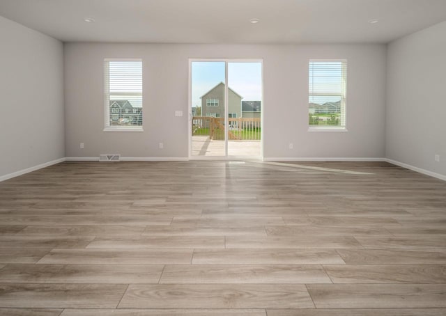 spare room featuring a healthy amount of sunlight and light hardwood / wood-style floors