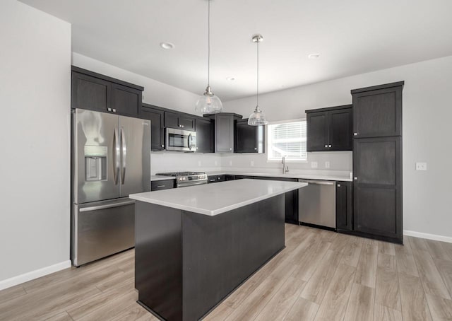 kitchen featuring sink, light hardwood / wood-style floors, appliances with stainless steel finishes, decorative light fixtures, and a kitchen island