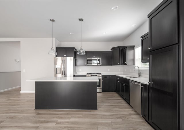 kitchen featuring sink, a center island, light hardwood / wood-style flooring, pendant lighting, and appliances with stainless steel finishes