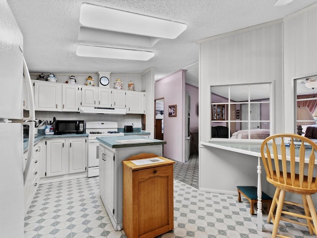 kitchen featuring a center island, white cabinetry, white appliances, and a textured ceiling