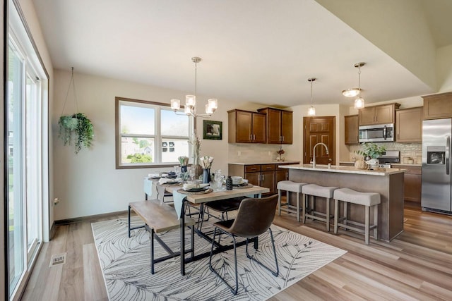 dining space with a chandelier, light hardwood / wood-style floors, and sink