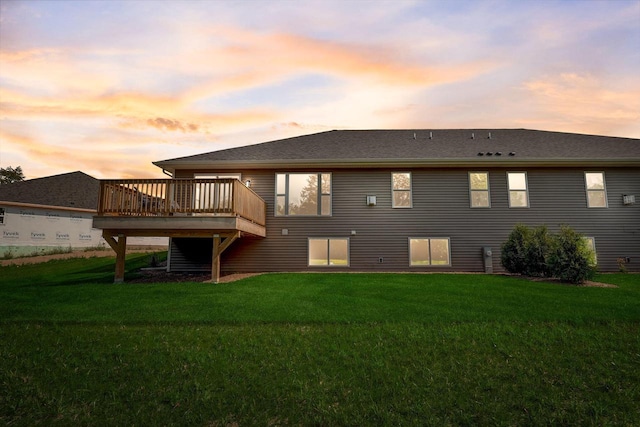 back house at dusk with a deck and a yard