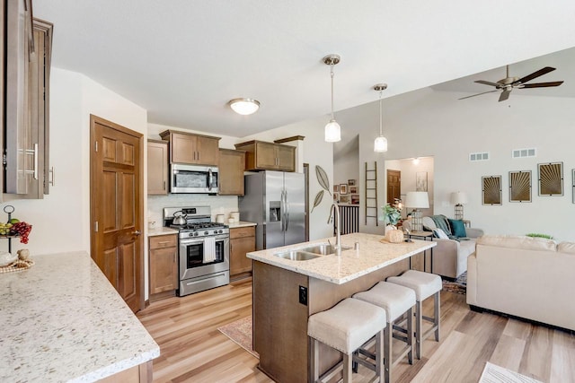 kitchen with appliances with stainless steel finishes, backsplash, decorative light fixtures, light stone countertops, and sink