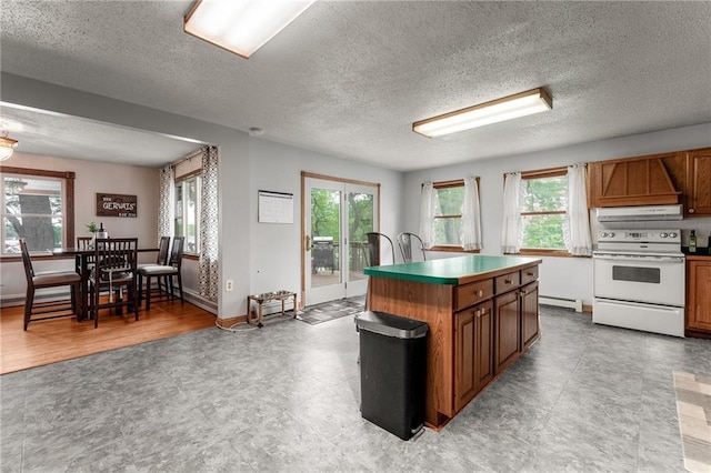 kitchen with a center island, electric stove, a textured ceiling, and a wealth of natural light