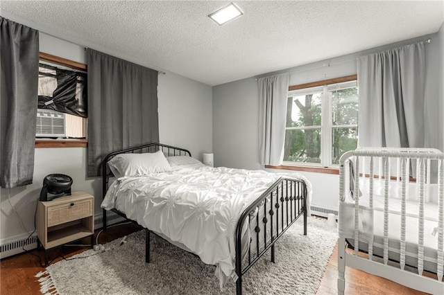 bedroom with hardwood / wood-style flooring, cooling unit, a textured ceiling, and a baseboard heating unit