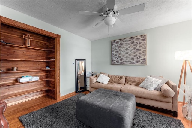 living room featuring a textured ceiling, ceiling fan, and dark wood-type flooring