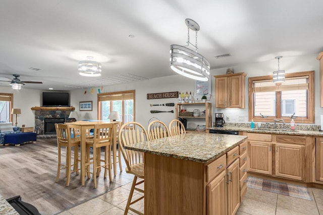 kitchen with light stone counters, a kitchen island, and hanging light fixtures