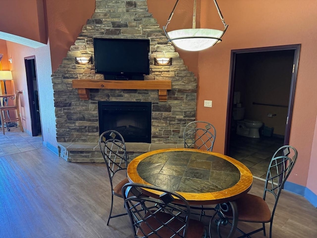 dining area featuring a stone fireplace and hardwood / wood-style flooring