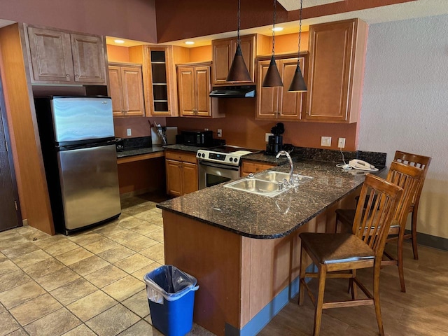 kitchen with dark stone counters, hanging light fixtures, sink, appliances with stainless steel finishes, and kitchen peninsula