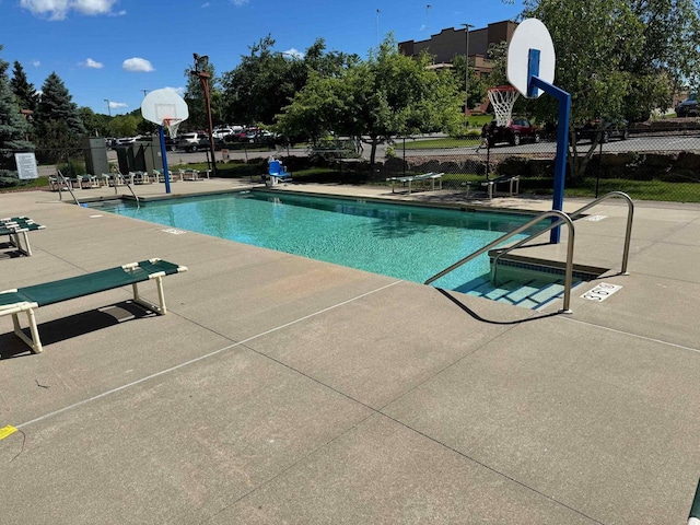 view of swimming pool with basketball hoop