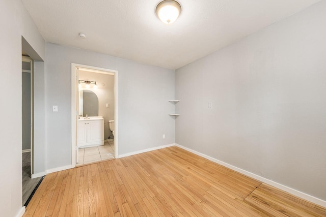 unfurnished bedroom featuring ensuite bath, light hardwood / wood-style flooring, and sink