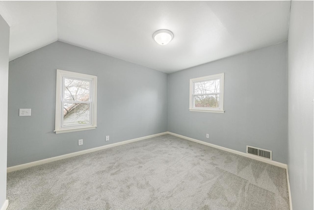 carpeted spare room featuring a wealth of natural light and lofted ceiling