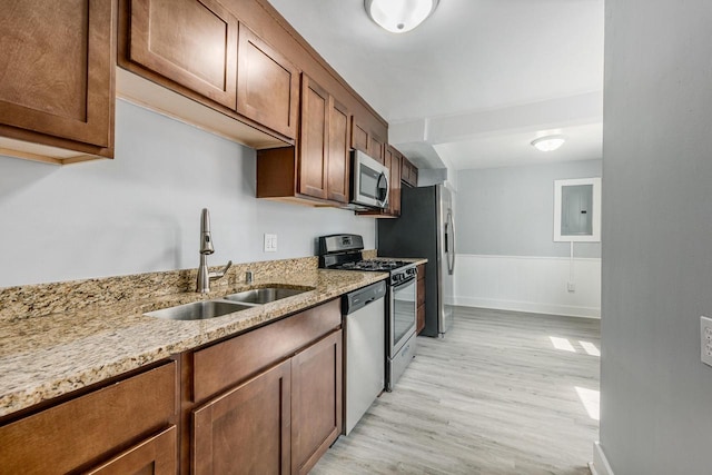 kitchen with light stone countertops, sink, stainless steel appliances, and light wood-type flooring