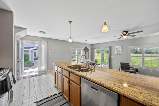 kitchen with hanging light fixtures, sink, light tile patterned floors, light stone countertops, and appliances with stainless steel finishes