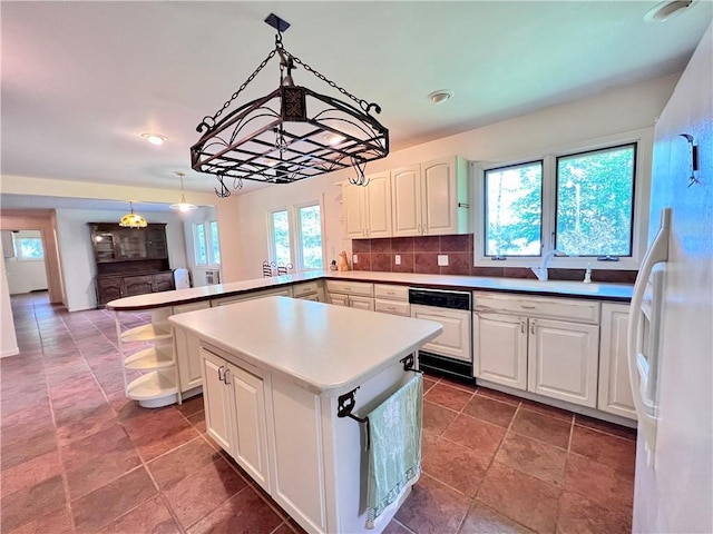 kitchen with white cabinetry, kitchen peninsula, a wealth of natural light, and tasteful backsplash