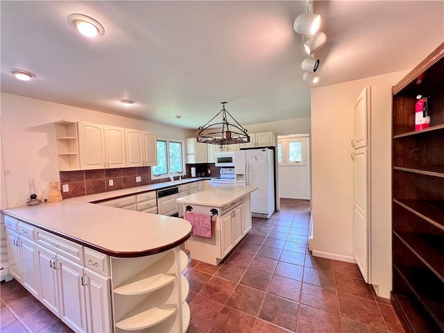 kitchen featuring kitchen peninsula, white appliances, white cabinets, a center island, and hanging light fixtures