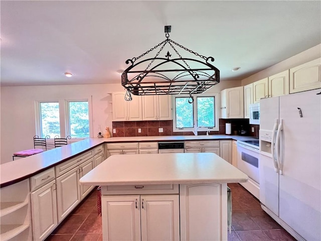 kitchen featuring sink, kitchen peninsula, decorative light fixtures, white appliances, and decorative backsplash