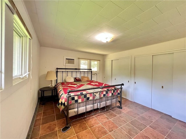 bedroom with two closets and a wall unit AC