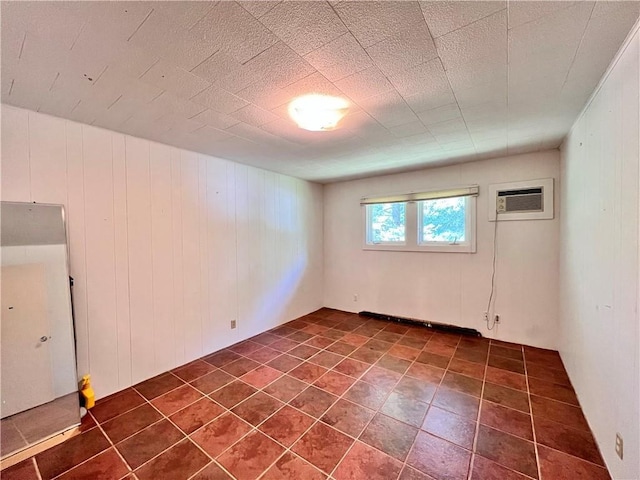 basement with a wall mounted air conditioner, dark tile patterned flooring, and wooden walls