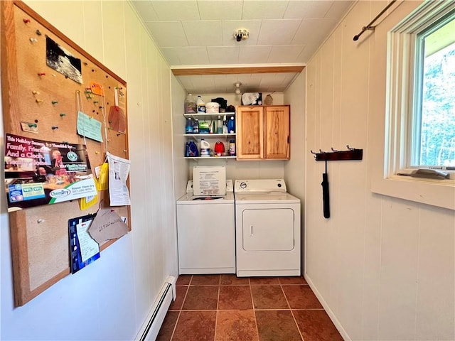 laundry area featuring cabinets, baseboard heating, wood walls, washer and dryer, and dark tile patterned flooring