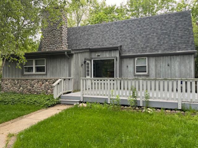 rear view of house featuring a wooden deck and a yard