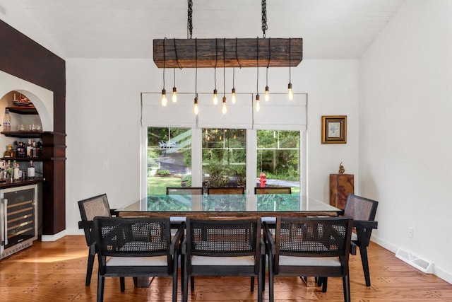 dining room featuring beverage cooler, wood-type flooring, and indoor bar