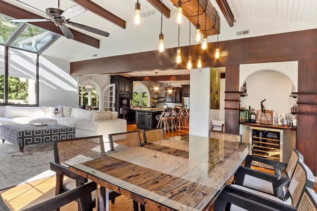 dining space with ceiling fan, hardwood / wood-style floors, beamed ceiling, and high vaulted ceiling