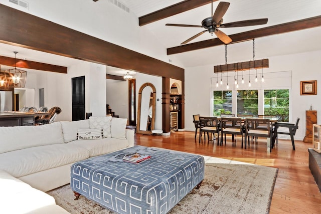 living room featuring beam ceiling, high vaulted ceiling, ceiling fan with notable chandelier, and hardwood / wood-style flooring