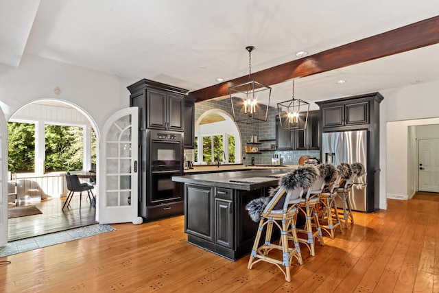 kitchen featuring tasteful backsplash, stainless steel refrigerator with ice dispenser, light hardwood / wood-style floors, a kitchen bar, and a kitchen island