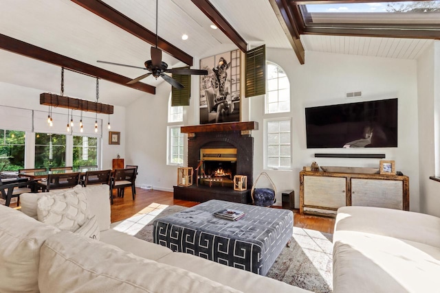 living room with beam ceiling, ceiling fan, a healthy amount of sunlight, and light wood-type flooring