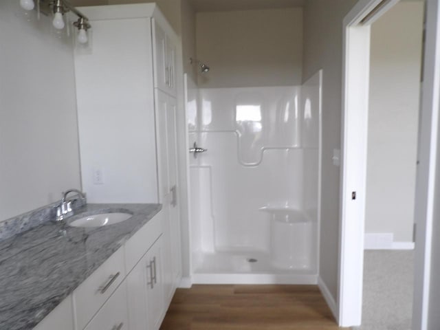 bathroom featuring a shower, vanity, and hardwood / wood-style flooring