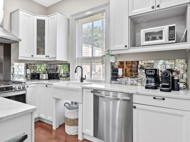 kitchen with stainless steel appliances, white cabinetry, and wall chimney range hood