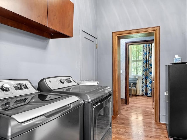 washroom featuring washer and dryer, light wood-type flooring, and cabinets