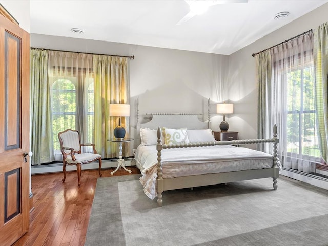 bedroom with hardwood / wood-style floors, a baseboard radiator, and ceiling fan