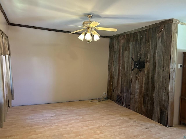 157 E 2nd St, Glidden, WI 54527 - empty room featuring ceiling fan, wooden walls, light hardwood / wood-style floors, and ornamental molding