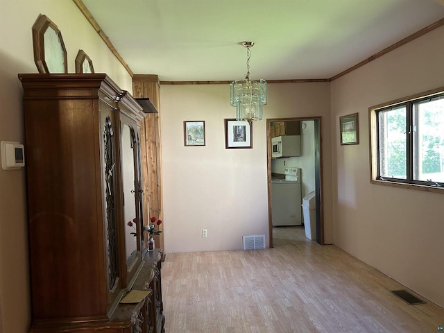 157 E 2nd St, Glidden, WI 54527 - dining space with washer / clothes dryer, light hardwood / wood-style flooring, ornamental molding, and an inviting chandelier