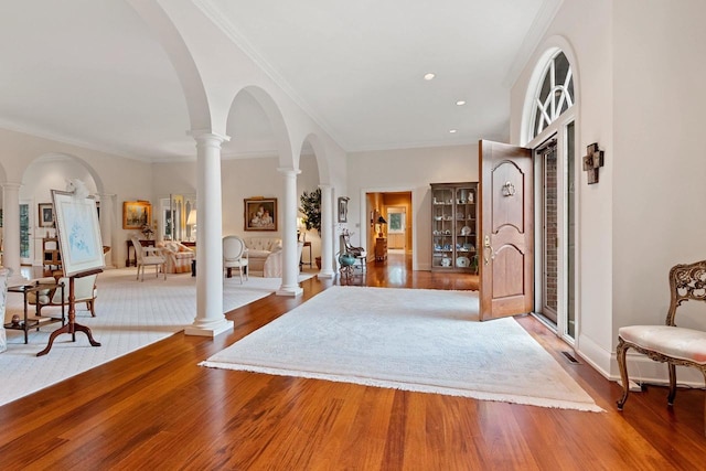 entryway featuring hardwood / wood-style floors, decorative columns, and crown molding