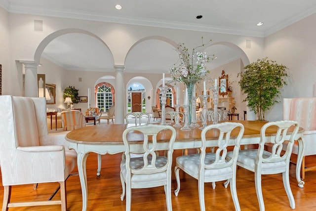 dining room featuring decorative columns, hardwood / wood-style floors, and ornamental molding