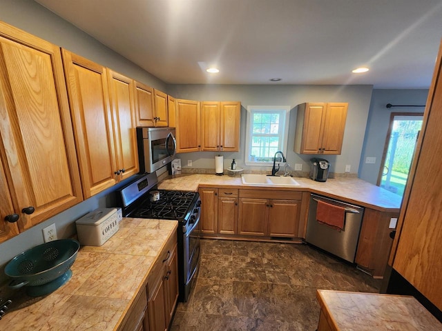 kitchen featuring tile countertops, sink, a healthy amount of sunlight, and appliances with stainless steel finishes