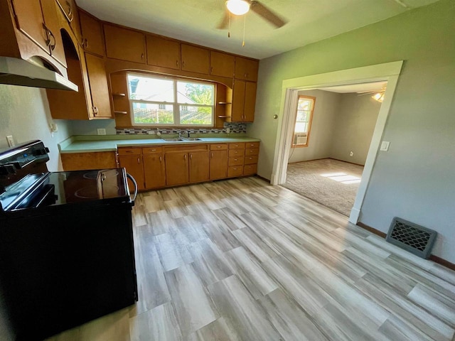 kitchen featuring black / electric stove, sink, ceiling fan, tasteful backsplash, and light colored carpet