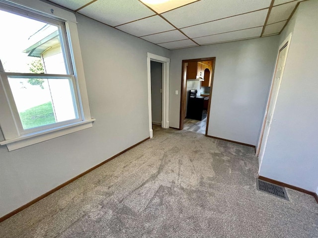 empty room featuring light carpet and a drop ceiling