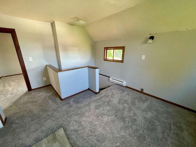 carpeted empty room with a baseboard heating unit and vaulted ceiling