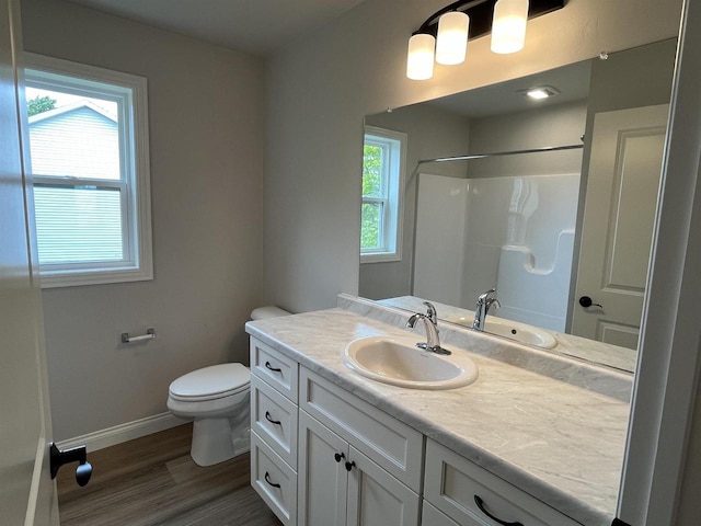 bathroom featuring toilet, vanity, a healthy amount of sunlight, and hardwood / wood-style flooring