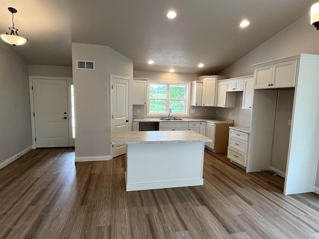 kitchen with sink, white cabinets, wood-type flooring, and a kitchen island