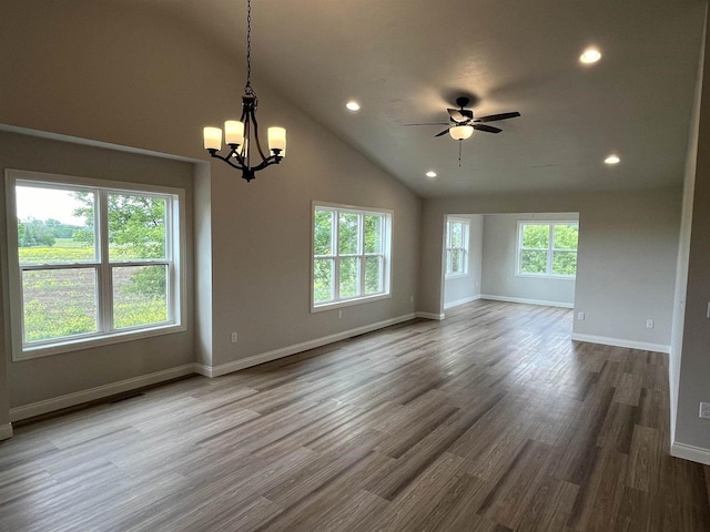 spare room with ceiling fan with notable chandelier, hardwood / wood-style flooring, and high vaulted ceiling