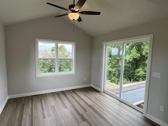 empty room featuring lofted ceiling, light wood-type flooring, and a healthy amount of sunlight