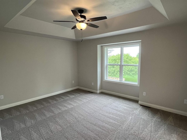 carpeted spare room featuring ceiling fan and a tray ceiling